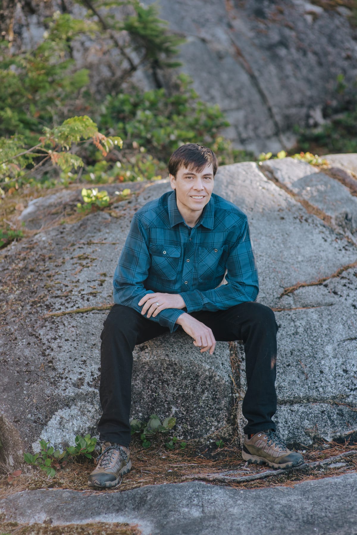 Chris Pettingill sitting on a granite outcrop above Squamish at golden hour